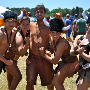 A group of people wear leather skirts and heats with horns.