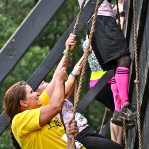 A selection of people work hard to use ropes to climb up a wall.