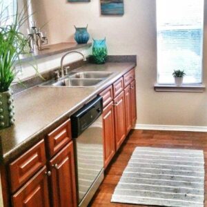 A narrow kicthen with a wide sink and a large window at the end.