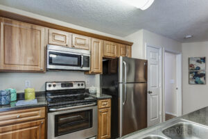 A narrow kitchen with medium-toned cabinets and nice appliances.