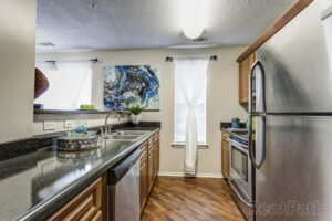 A narrow kitchen with modern, silver appliances.