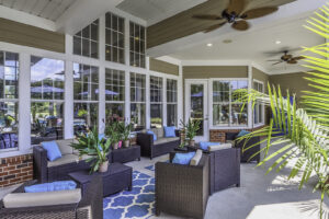 A comfortable covered patio with ceiling fans, palms, and chairs.
