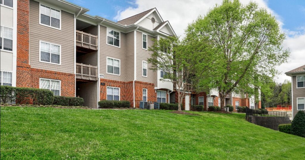 A set of apartments with a green lawn in front.
