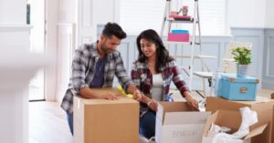 A man and woman unpack their boxes in a new space.