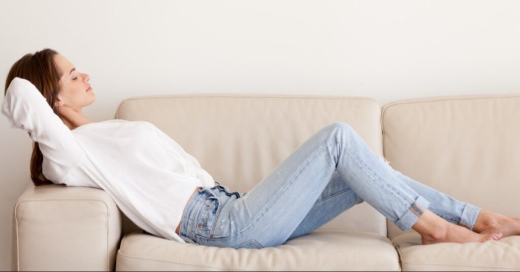 A white couch with a woman reclining on it.