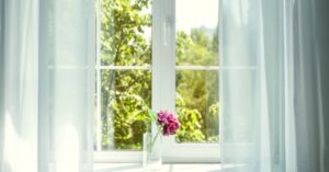 A window looking out at trees is framed by gauzy white curtains.