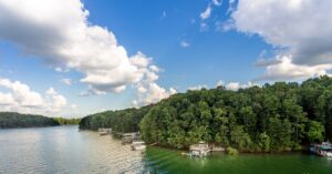 A very green land mass overlooks a lake with docks jutting into the water.