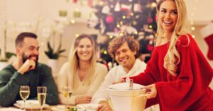 A group of people eat at a table with a Christmas tree in the background.