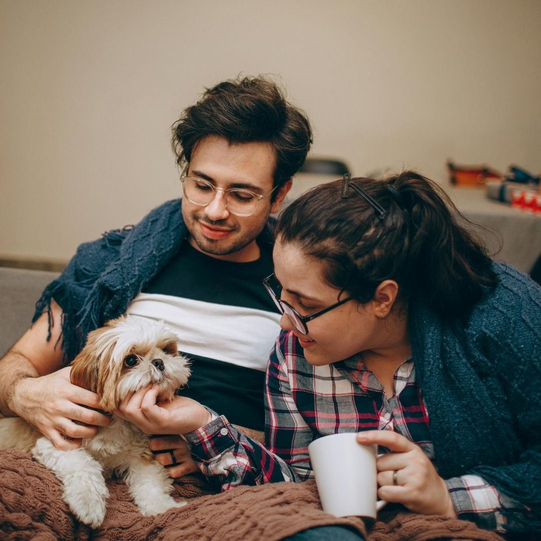 Two dog owners petting their dog.